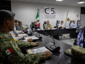 Funcionarios y militares en una sala de juntas del C5i con bandera de México y escudo estatal