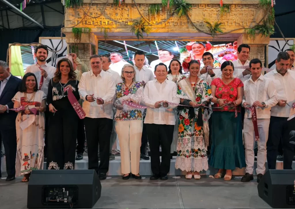 Grupo de personas vestidas formalmente, algunas con ropa tradicional, realizando un corte de listón en ceremonia