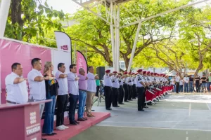 Grupo de personas en ceremonia oficial con banda de música y personas tomando protesta en cancha techada