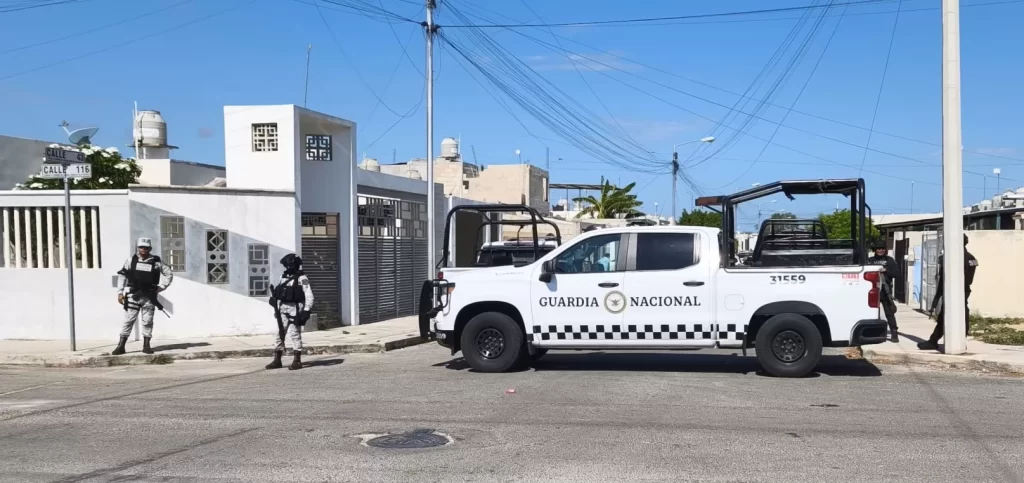 Pick up blanco de la Guardia Nacional con tres agentes de uniforme y chaleco antibalas en una esquina de calle residencial ba