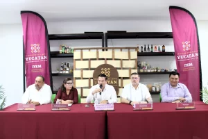 Cinco personas sentadas en mesa con manteles rojos en conferencia del Instituto Yucateco de Emprendedores