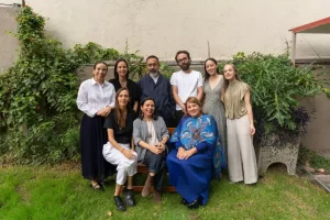 Diez personas posan juntas en un jardín con césped y plantas al fondo
