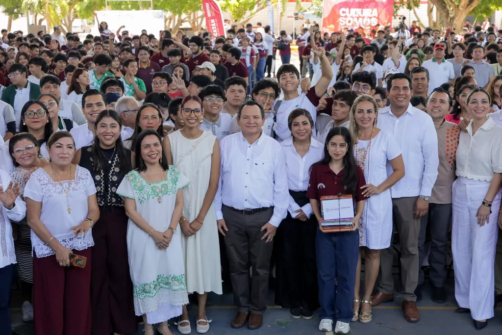 Grupo grande de personas posando para foto en evento con árboles y elementos culturales al fondo