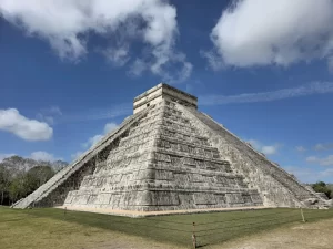 Vista lateral de la pirámide de Chichén Itzá con cielo azul y algunas nubes