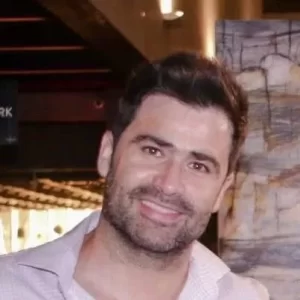Hombre joven con barba y cabello oscuro sonriendo levemente dentro de un lugar cerrado