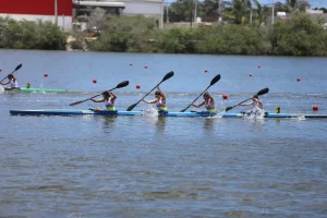 Cuatro mujeres remando sincronizadas en kayak azul durante una carrera en el agua
