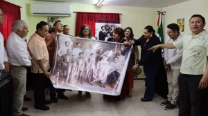 Grupo de personas sosteniendo y mostrando una fotografía antigua en interiores