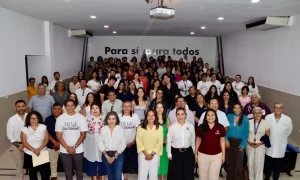 Grupo numeroso de personas en salón con letrero al fondo que dice 'Para sí y para todos'