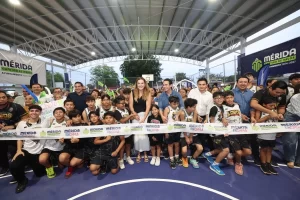 Grupo de niños y adultos en la inauguración de una cancha deportiva techada en Mérida, cortan la cinta oficial