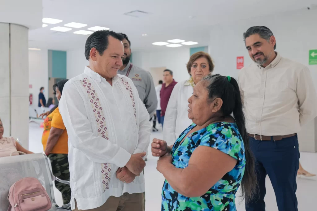 Hombre con guayabera blanca conversando con mujer de blusa azul con estampado