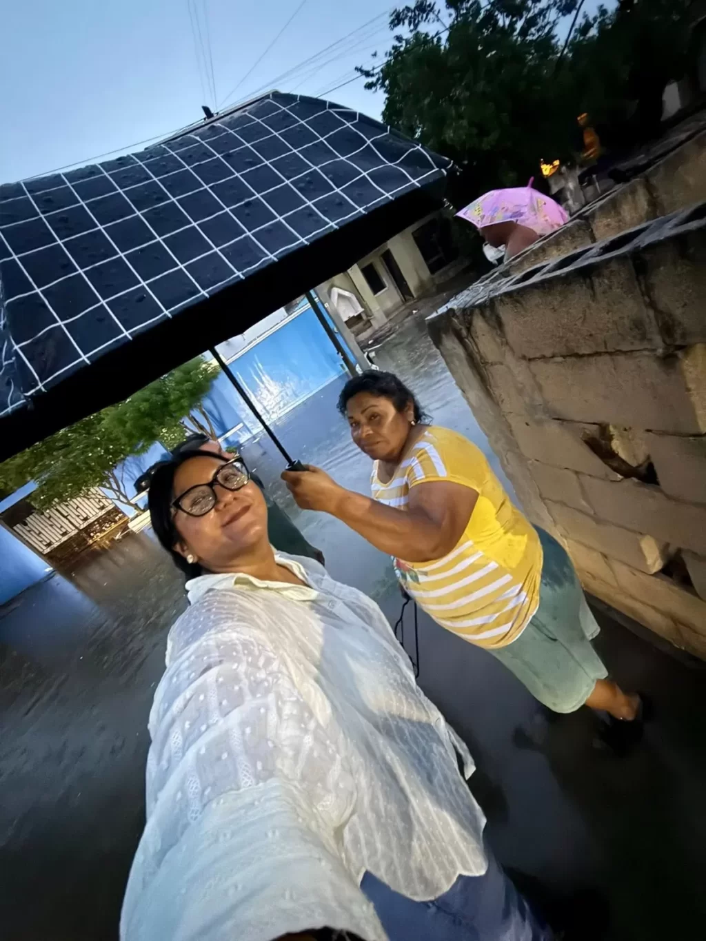 Dos mujeres bajo paraguas en calle inundada durante lluvia