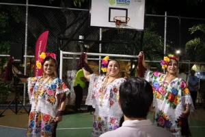 Tres mujeres bailando vestidas con trajes típicos de Yucatán con flores en el cabello y joyería tradicional