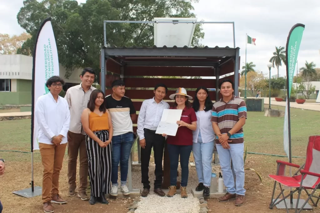 Ocho jóvenes posando frente a módulo con banderas de la Universidad Tecnológica Metropolitana
