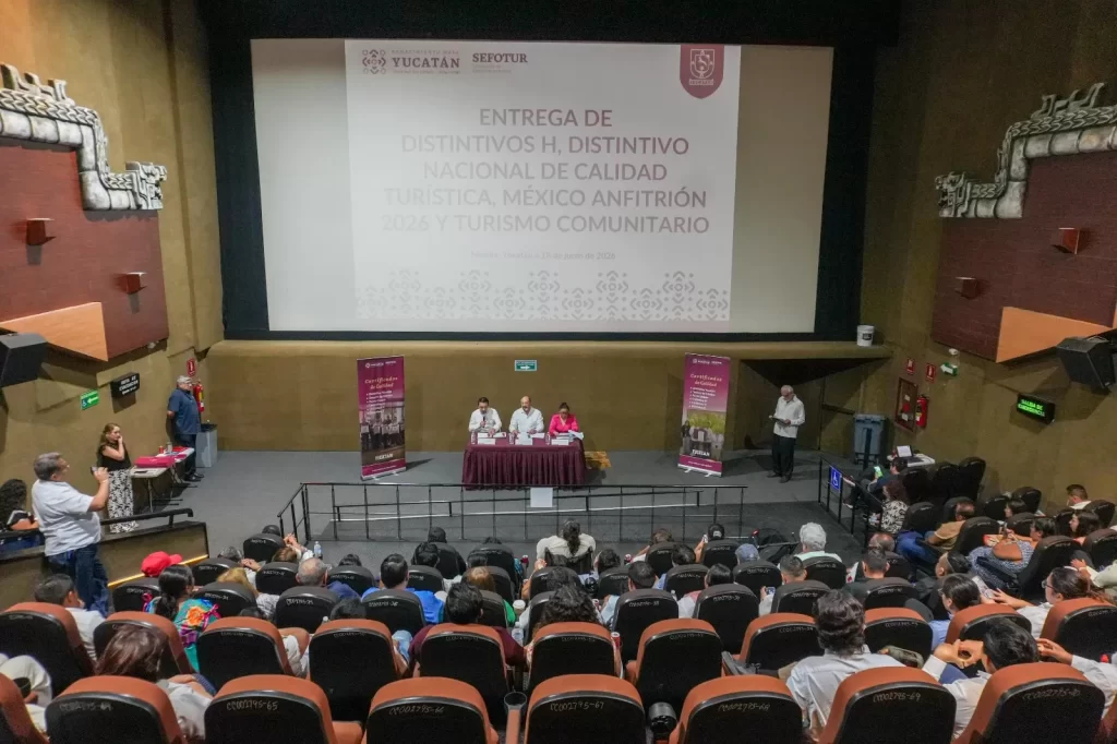 Evento de entrega de distintivos de calidad turística en auditorio con audiencia y mesa de ponentes