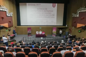 Evento de entrega de distintivos de calidad turística en auditorio con audiencia y mesa de ponentes