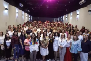 Gran grupo de personas posando en una sala, varias uniformadas con gorras rojas y chalecos, otras con vestimenta formal