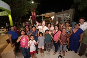 Grupo de personas de varias edades sonriendo y saludando en un parque iluminado por la noche