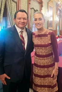 Hombre y mujer de pie juntos en salón con cortinas y candelabros al fondo