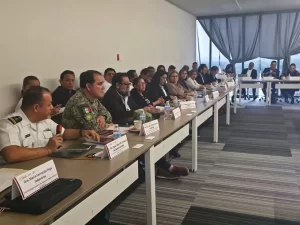 Profesionales y autoridades sentados en mesa larga en sala de juntas durante reunión formal