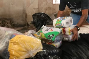 Mano acomodando paquetes de víveres con comida y productos básicos dentro de bolsas negras