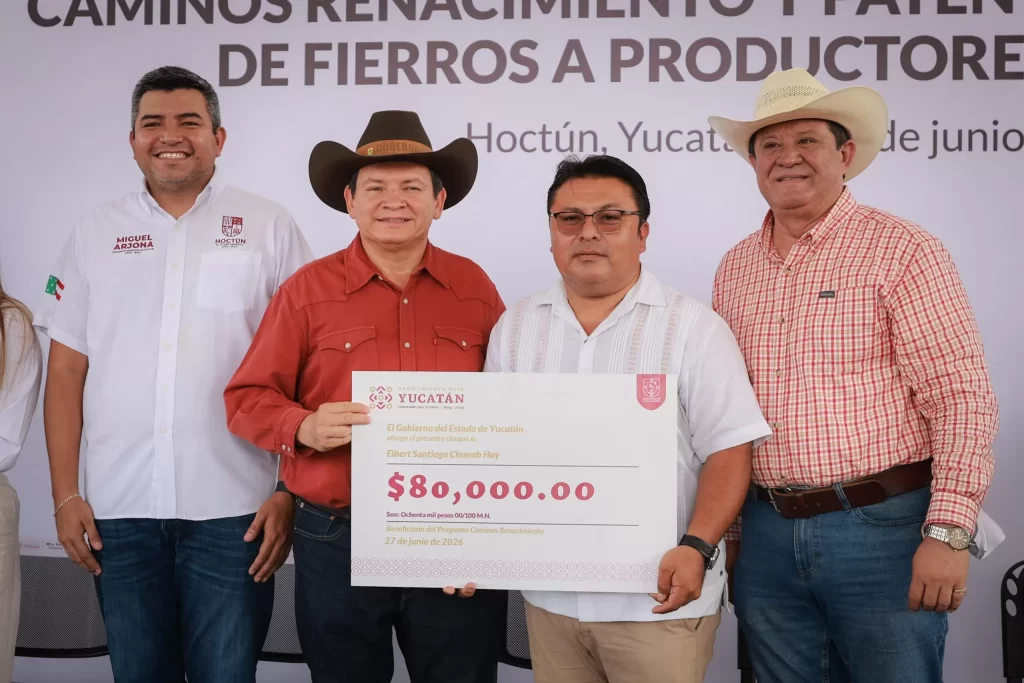 Cuatro hombres posando mientras uno sostiene un cheque simbólico de 80 mil pesos en Hoctún, Yucatán