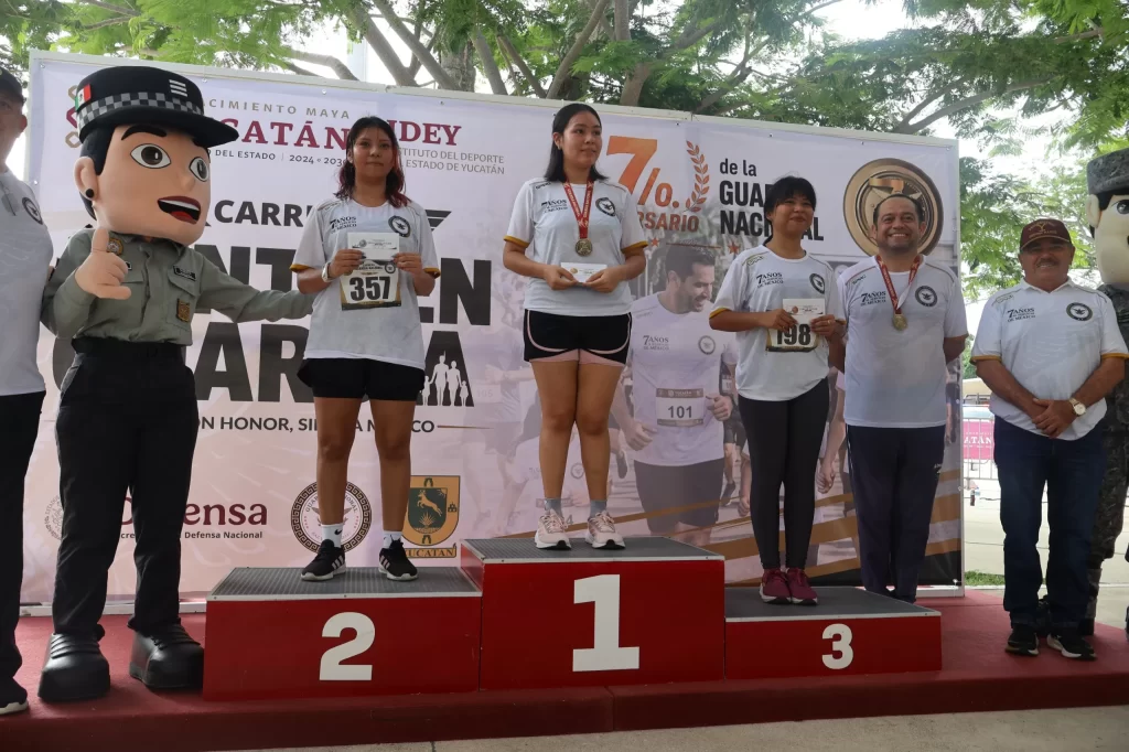 Tres mujeres y un hombre con medallas y premios en podio de carrera deportiva en Yucatán