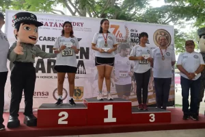 Tres mujeres y un hombre con medallas y premios en podio de carrera deportiva en Yucatán