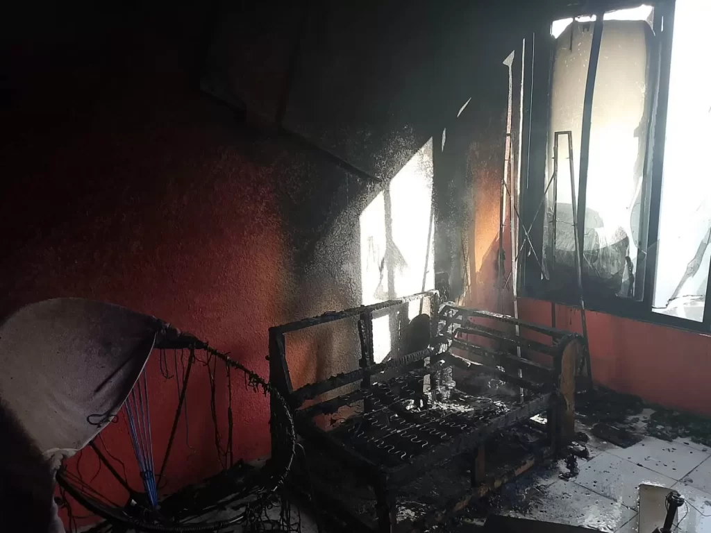 Sala con sillones quemados y ventanas dañadas por incendio