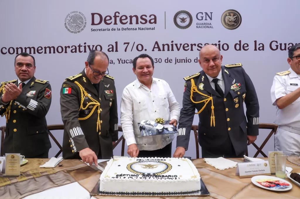 Funcionarios militares y civil en ceremonia con pastel del 7o aniversario de la Guardia Nacional en Yucatán