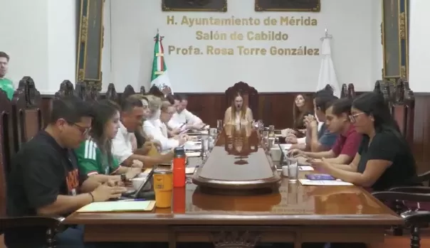 Personas sentadas en mesa larga dentro del Salón de Cabildo Profa. Rosa Torre González en Mérida