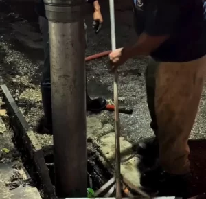 Persona trabajando con herramienta en reparación de pavimento durante la noche