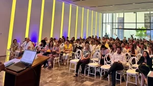 Personas sentadas en sala con sillas blancas durante una conferencia o presentación