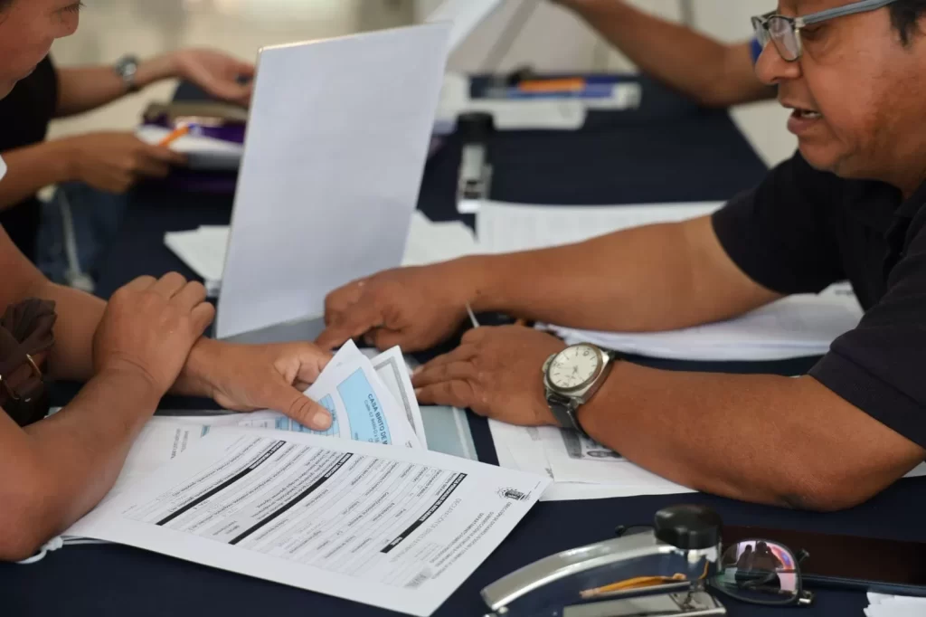 Personas revisando documentos oficiales sobre una mesa con superficie oscura