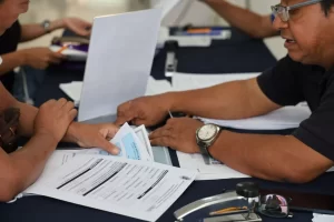 Personas revisando documentos oficiales sobre una mesa con superficie oscura