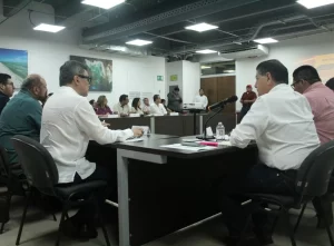 Personas en reunión sentadas alrededor de mesas en forma de U en una sala con iluminación led y arte en las paredes