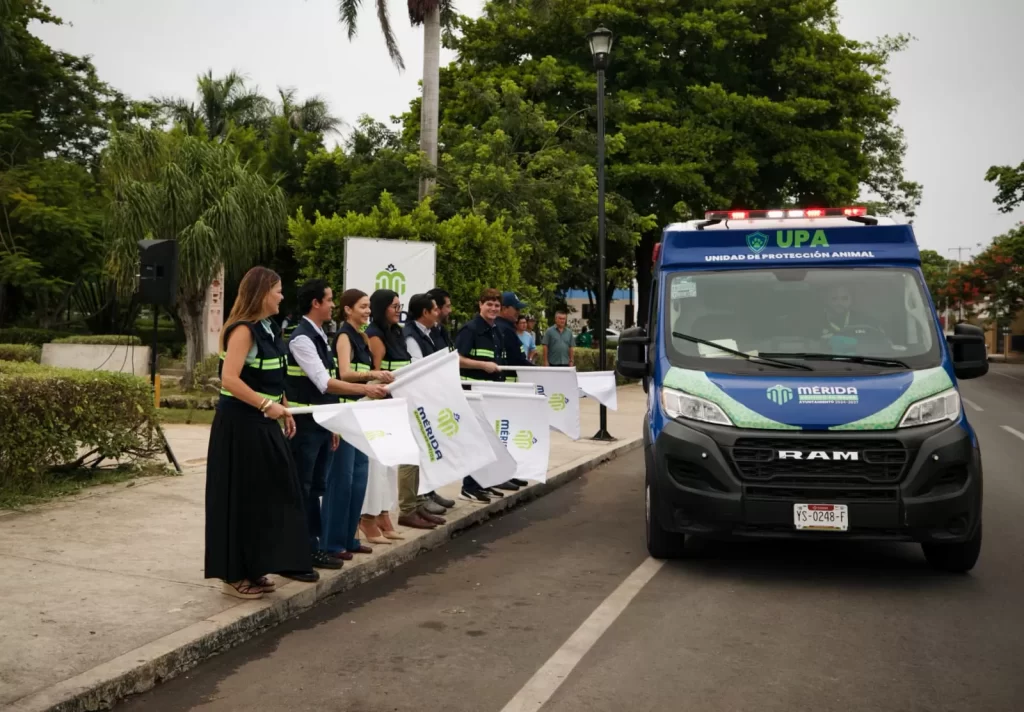 Personas saludando desde la banqueta a una unidad azul de Protección Animal en Mérida