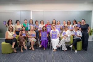 Grupo de mujeres posando con carteles y tarjetas púrpuras que dicen 'ALTO' y mensajes contra la explotación sexual infantil