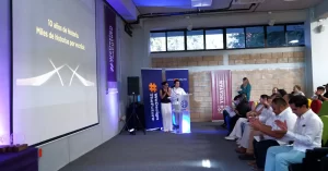 Personas en un evento dentro de la Universidad Politécnica de Yucatán, dos personas en podio y audiencia sentada