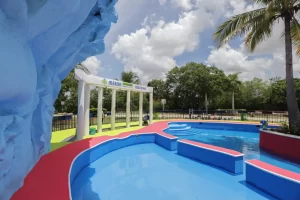 Piscina vacía con estructura azul y arco blanco con columnas y señalización de regaderas en Mérida