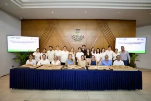 Grupo de personas posando en un evento oficial con maquetas arquitectónicas en una mesa frente a ellos