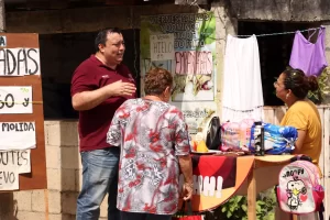Tres personas en puesto callejero con anuncios de venta de empanadas y hielo